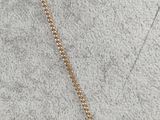 a woman wearing a gold chain necklace with a gold disc pendant