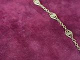 a close up of a gold chain necklace on a purple velvet surface