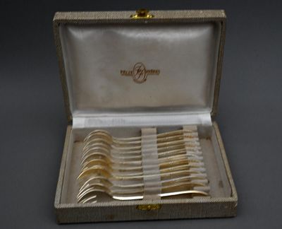 des couverts dans un coffret posé sur une table, sur fond noir