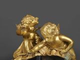paire de figurines dorées représentant des chérubins, posées sur un socle en marbre