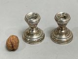 two silver candlesticks sitting next to a walnut