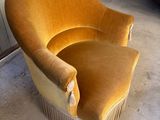 une chaise de couleur moutarde, ornée de franges et dotée de pieds en bois, dans un garage