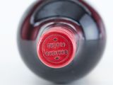 a close up of a wine bottle with a red cap