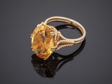 a close up of a ring with a yellow stone on a black surface