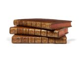 trois vieux livres empilés sur une surface blanche