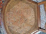 a wooden chair with a wicker seat on a rug