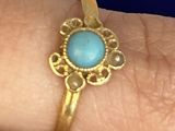 Quelqu'un tient une bague en or sertie d'une turquoise.