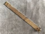 un gros plan d'un bracelet en or posé sur un tissu gris