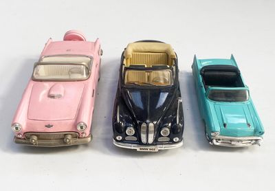 trois petites voitures sont alignées sur une surface blanche