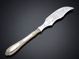 a silver knife on a black surface with a black background