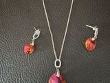 un ensemble composé d'un collier et de boucles d'oreilles ornés de cristaux roses sur un fond en cuir noir