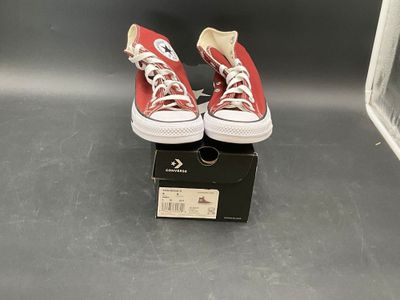 pair of red converses sitting on top of a black box