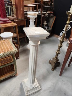 a white pedestal in the middle of a room filled with antiques