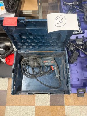 une boîte à outils bleue remplie d'outils, posée sur un sol à carreaux