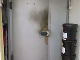 une poubelle noire posée devant une porte blanche