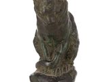 bronze statue of a bear sitting on a rock on a white background