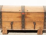 an old wooden chest sitting on top of a sidewalk next to a white wall