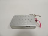an old metal box with a pink ribbon on a white surface
