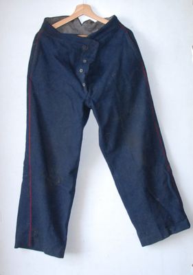 denim pants hanging on a hanger on a white wall