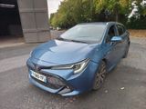 La Toyota Corolla bleue est garée devant un garage.