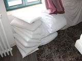 une pile d'oreillers posée sur un lit, à côté d'un radiateur