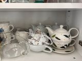 many cups and saucers on a shelf in a cabinet