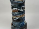 a blue and brown vase sitting on a white surface