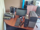 un bureau sur lequel se trouvent un ordinateur, une imprimante et d'autres appareils électroniques
