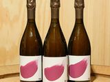 trois bouteilles de vin posées sur un tonneau en bois