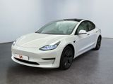une Tesla Model 3 blanche garée dans une pièce blanche
