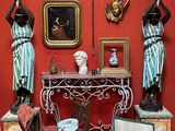 une pièce avec une table, une chaise, des vases et des statues