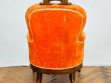 an orange chair sitting on top of a wooden floor next to a white wall