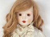 a white doll with long red hair and a white dress