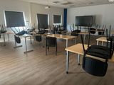 une salle où se trouvent plusieurs bureaux et chaises