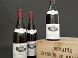 three bottles of wine are in a wooden box on a table