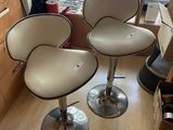 two white leather bar stools sitting on top of a hard wood floor