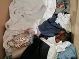 a cardboard box filled with clothes and a blanket