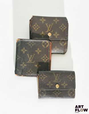 trois portefeuilles Louis Vuitton posés sur une surface blanche