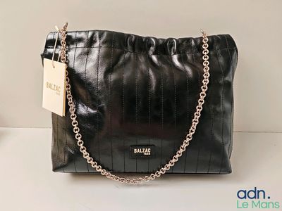 black leather handbag with chain strap and name tag on it