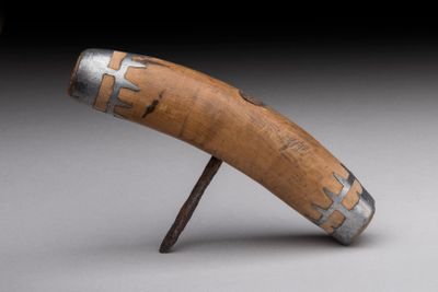 un objet en bois muni d'une poignée métallique, posé sur une surface grise