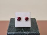 a pair of red cubicge earrings sitting on top of a marble block