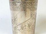 une tasse en argent antique avec un motif floral sur le bord