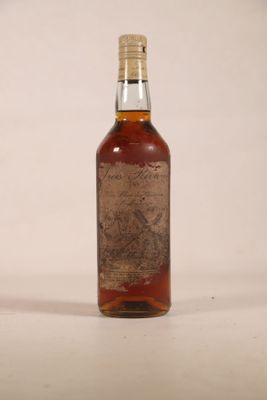 une vieille bouteille de whisky posée sur une surface blanche