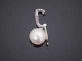 a white pearl and diamond pendant on a black background