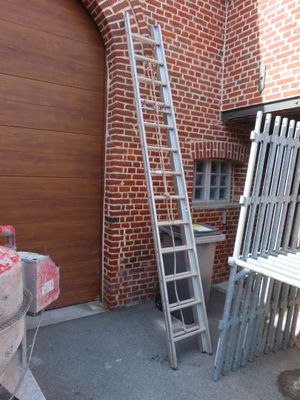 une échelle appuyée contre un mur de briques, à côté d'une table