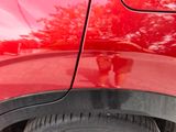 a close up of a red car with a reflection of a person on the side of the car