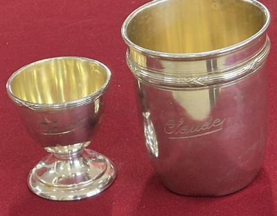 une coupe en argent à côté d'une autre coupe en argent, posées sur une table rouge