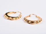 two pairs of gold hoop earrings on a white surface