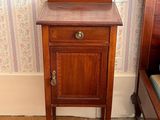 a small table with a drawer on it in the corner of a room
