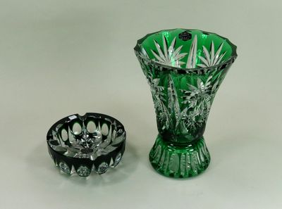 un vase en verre vert à côté d'un cendrier en verre noir